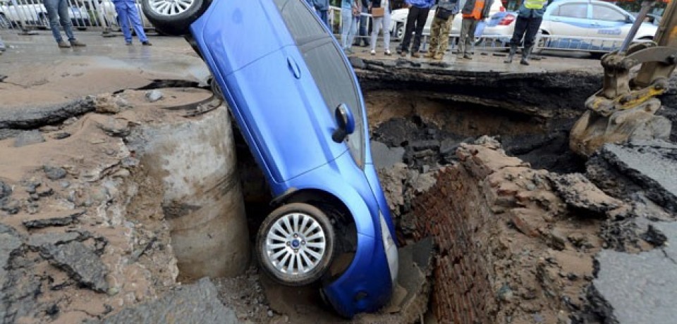 Motorista escapa ileso após carro cair em cratera na China